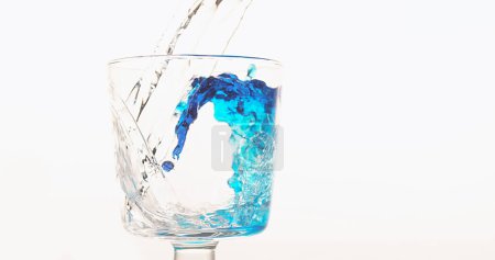 Photo for Water being poured into Glass against White Background, blue in the bottom of the glass - Royalty Free Image
