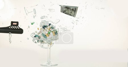 Photo for Glass filled with Capsules and Dollars Exploding against White Background - Royalty Free Image
