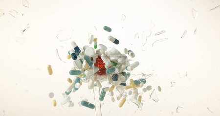 Photo for Glass filled with Capsules Exploding against White Background - Royalty Free Image