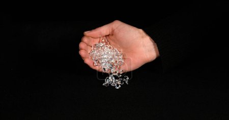 Téléchargez les photos : Diamants tombant dans la main sur fond noir - en image libre de droit