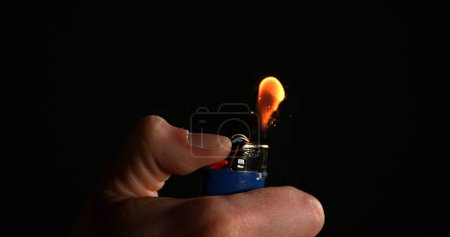 Photo for Lighter in Hand with Flame against Black background - Royalty Free Image
