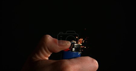 Foto de Encendedor en mano con llama contra fondo negro - Imagen libre de derechos
