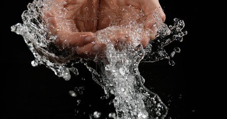 Téléchargez les photos : Les mains de la femme et de l'eau sur fond noir - en image libre de droit
