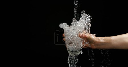 Photo for Woman's Hands and Water Flowing in Glass on Black Background - Royalty Free Image