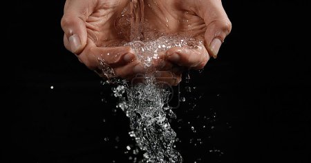 Téléchargez les photos : Les mains de la femme et de l'eau sur fond noir - en image libre de droit