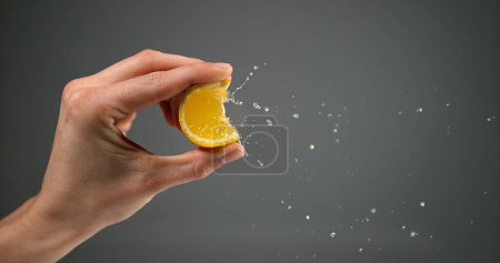 Foto de Mano de mujer apretando naranja contra fondo negro - Imagen libre de derechos