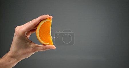 Téléchargez les photos : Main de femme serrant orange sur fond noir - en image libre de droit