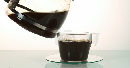 Téléchargez les photos : Café versé dans une tasse sur fond blanc - en image libre de droit