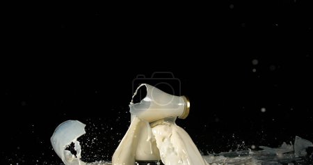 Foto de Botella de leche explotando contra fondo negro - Imagen libre de derechos