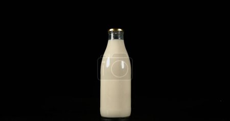 Téléchargez les photos : Bouteille de lait sur fond noir - en image libre de droit