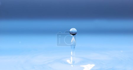 Foto de Gota de agua cayendo en el agua sobre fondo azul - Imagen libre de derechos