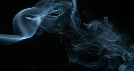 Téléchargez les photos : Fumée de cigarette s'élevant sur fond noir - en image libre de droit