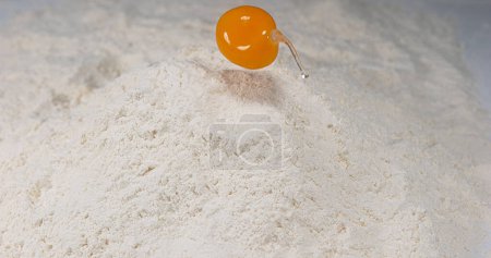 Foto de Huevo cayendo en harina contra fondo blanco, - Imagen libre de derechos