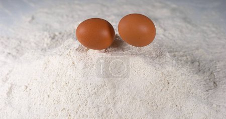 Foto de Huevo cayendo en harina contra fondo blanco, - Imagen libre de derechos