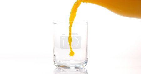 Foto de Zumo de naranja que se vierte en vidrio contra fondo blanco - Imagen libre de derechos