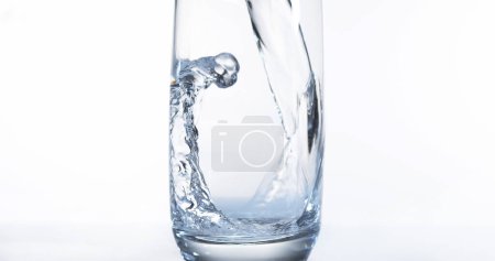 Téléchargez les photos : L'eau étant versée dans le verre sur fond blanc - en image libre de droit
