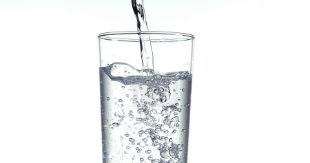 Téléchargez les photos : L'eau étant versée dans le verre sur fond blanc - en image libre de droit
