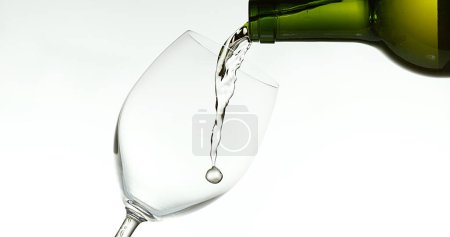 Foto de Vino blanco que se vierte en vidrio, contra fondo blanco - Imagen libre de derechos
