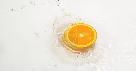Foto de Naranja, citrus sinensis, Slice Falling on Water y salpicaduras, contra fondo blanco - Imagen libre de derechos