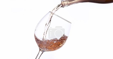 Foto de Vino rosado que se vierte en vidrio, contra fondo blanco - Imagen libre de derechos