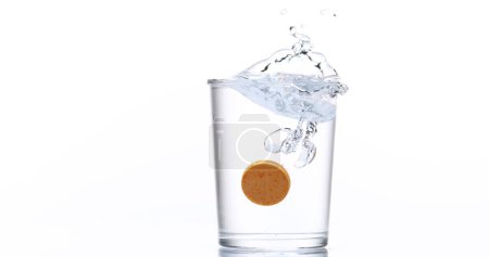 Photo for Tablet or Vitamin Falling and Dissolving into a Glass of Water against White Background - Royalty Free Image