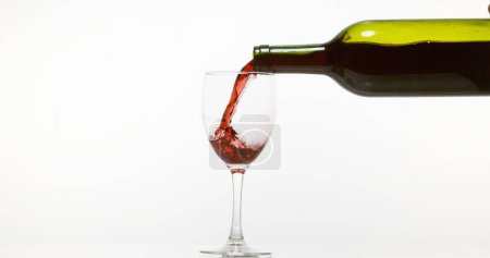 Photo for Red Wine being poured into Glass, against White Background - Royalty Free Image