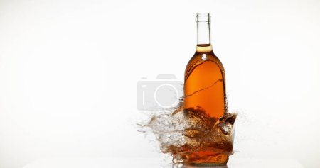 Foto de Botella de vino rosa rompiendo y salpicando contra fondo blanco - Imagen libre de derechos