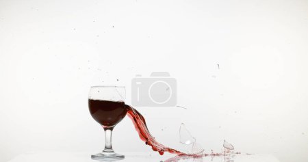 Photo for Glass of Red Wine Breaking and Splashing against White Background - Royalty Free Image