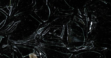 Photo for Stone breaking Pane of Glass against Black Background - Royalty Free Image