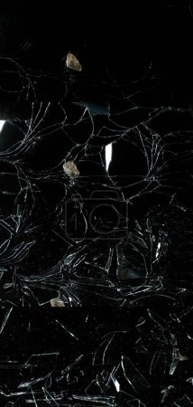 Photo for Stone breaking Pane of Glass against Black Background - Royalty Free Image
