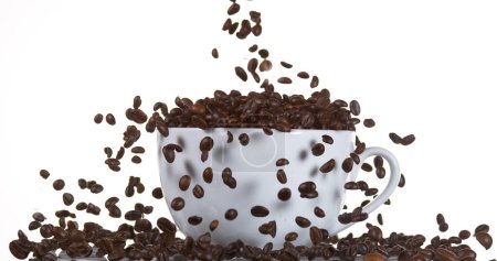 Foto de Granos de café cayendo en una taza contra fondo blanco - Imagen libre de derechos