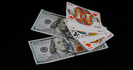 Téléchargez les photos : Jouer aux cartes tombant sur des billets en dollars sur fond noir - en image libre de droit