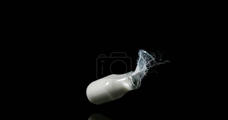 Photo for Bottle of Milk Falling and Exploging against Black Background - Royalty Free Image