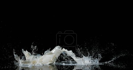 Téléchargez les photos : Bouteille de lait tombant et explosant sur fond noir - en image libre de droit