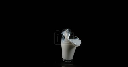 Téléchargez les photos : Verre pour le lait explosant sur fond noir - en image libre de droit