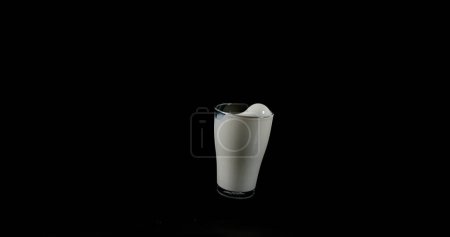 Photo for Glass for Milk exploding against Black Background - Royalty Free Image