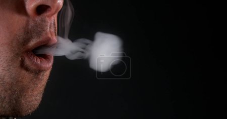 Photo for Man smoking a Cigarette against Black Background - Royalty Free Image