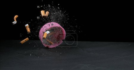 Photo for Ashtray filled with Megots falling on Black Background - Royalty Free Image
