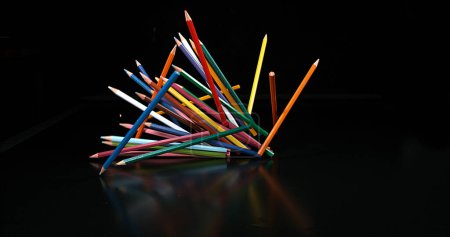 Téléchargez les photos : Crayons de couleur tombant sur fond noir - en image libre de droit