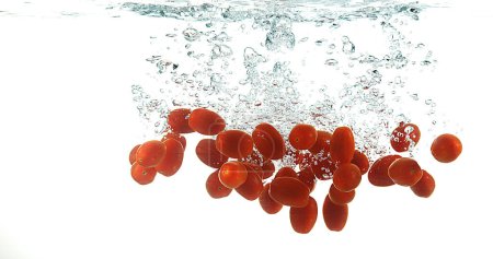 Téléchargez les photos : Tomates cerises, solanum lycopersicum, Fruits tombant dans l'eau sur fond blanc - en image libre de droit