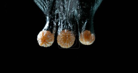 Foto de Clementinas, cítricos reticulados, Frutas que caen al agua contra el fondo negro - Imagen libre de derechos