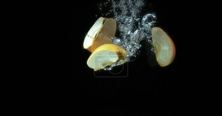Téléchargez les photos : Pommes, malus domestica, fruits entrant dans l'eau sur fond noir - en image libre de droit