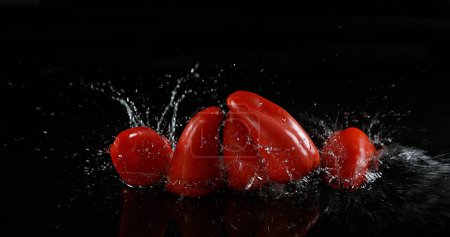 Foto de Pimientos dulces rojos, capsicum annuum, vegetal que cae sobre el agua contra el fondo negro - Imagen libre de derechos