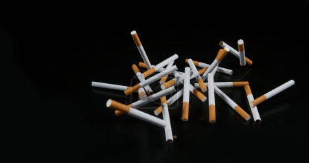 Téléchargez les photos : Cigarettes tombant sur fond noir - en image libre de droit