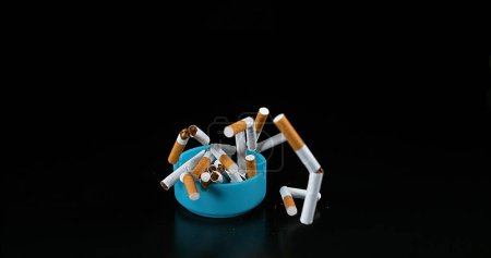 Photo for Ashtray and Cigarettes Falling against Black Background - Royalty Free Image