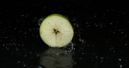 Photo for Granny Smith Apple, malus domestica, Slice turning on Water against black Background - Royalty Free Image