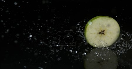 Photo for Granny Smith Apple, malus domestica, Slice turning on Water against black Background - Royalty Free Image