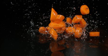 Téléchargez les photos : Carottes, carottes de daucus, Légumes tombant sur l'eau sur fond noir - en image libre de droit