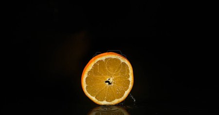 Téléchargez les photos : Orange, agrumes sinensis, Fruits tombant sur l'eau sur fond noir - en image libre de droit