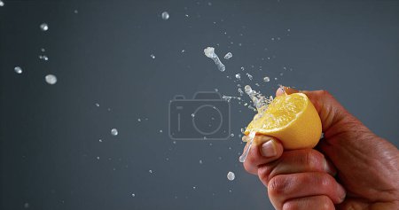 Foto de Mano del hombre exprimiendo limón, limonum cítrico contra fondo negro - Imagen libre de derechos